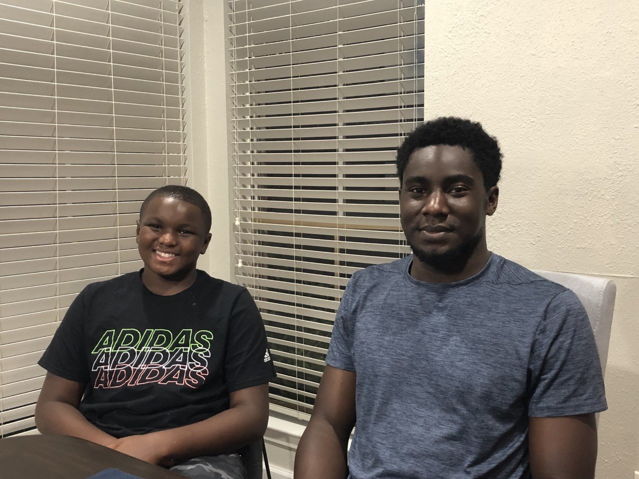 Julian and Jaylan Gray share their story of perseverance. They are sitting at their mother’s table, which was restored, along with their house, after flood and winter storm damage.